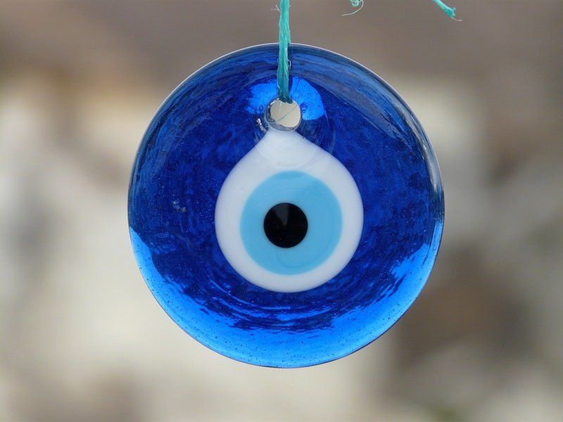 A glass evil eye amulet hanging from string.